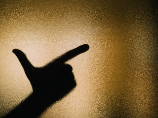 Silhouette of hand making a revolver on a glass.