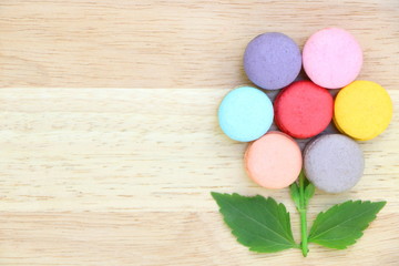 Closeup top view of colorful macarons stack like flower on wood background have copy space. Flat lay style.