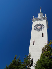 Obraz premium The clock tower of Sochi railway station on a background of blue sky.
