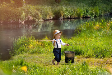Portrait of cute caucasian blondie baby boy with fishing rod in country side background. Nature, outdoors, childhood concept