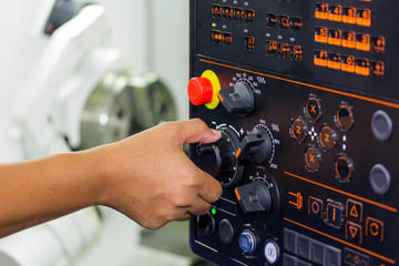 operator use hand turns dial switch control at panel for adjust parameter of cnc lathe machine at factory