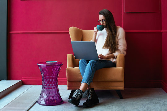 Image of happy woman using laptop while sitting at cafe. Young american woman sitting in a coffee shop and working on laptop.