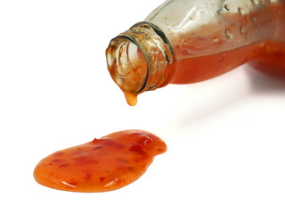 close up of chili sauce dripping from glass bottle isolated on white background