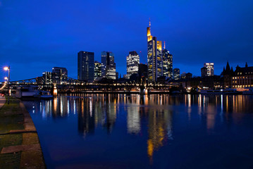Fototapeta na wymiar Blick über den Main auf die Skyline von Frankfurt am Main in Hessen, Deutschland zur blauen Stunde 