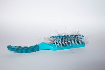 Hair fall out. Hairbrush with hair on a white background. Comb in hand. 