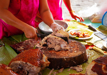 Lechon national philippine dish with waitress hand. Woman sells fried pork in Asian country