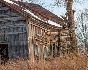 sagging decaying weathered abandoned house in winter with rusty roof