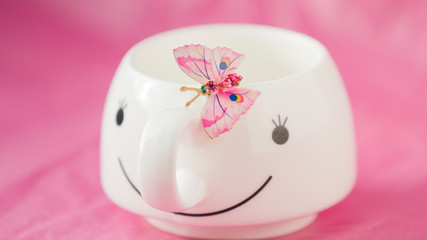 On a pink background with white Cup and pink butterfly