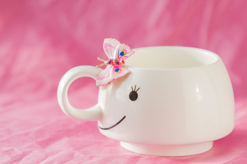 On a pink background with white Cup and pink butterfly