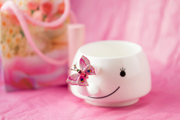 On a pink background with white Cup and pink butterfly