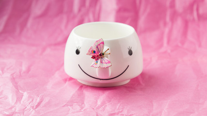 On a pink background with white Cup and pink butterfly