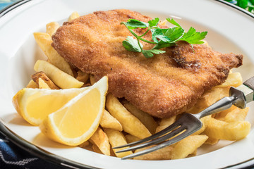 A piece of fried cod with fries on a plate.