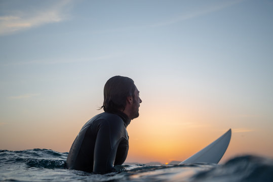 surfer sitting on the surfboard at sunset