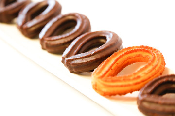 small chocolate spanish fritters in a white dish on white background