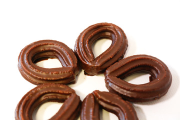 small chocolate spanish fritters on flower shape on white background