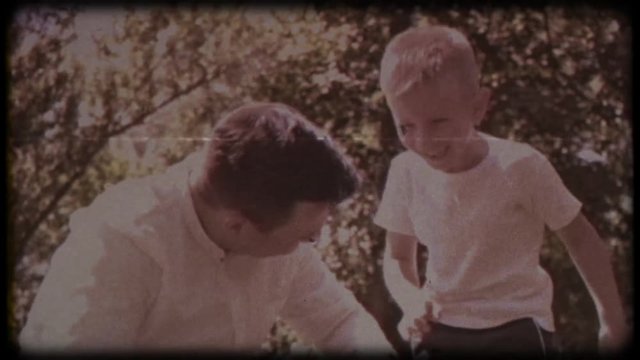 Family video archive. Retro camera 8&nbsp;mm. Old film. Father with his son blowing soap bubbles, fun family pastime, a child having fun with his dad