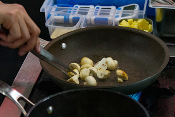 chef cooking stir fry mushroom sliced in pan