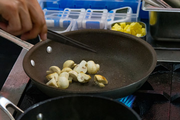 chef cooking stir fry mushroom sliced in pan