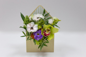 Wonderful floral arrangement of fresh flowers in a box in the form of an envelope on a light...