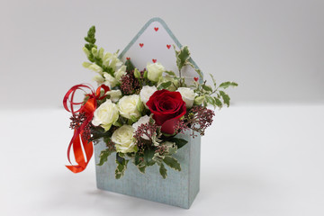 Cute floral arrangement (gift) of fresh flowers in a box in the form of an envelope on a light...