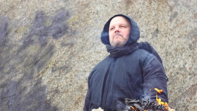 ancient warlock near stone wall with burning book - war concepts