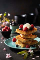 Freshly baked waffles with raspberries, berries, honey and coffee for breakfast or brunch on a dark background with copy space. Homemade Dessert concept.