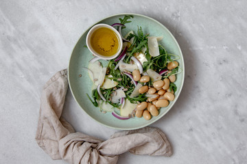 Vegan salad with beans arugula onions apple and vegan parmesan cheese