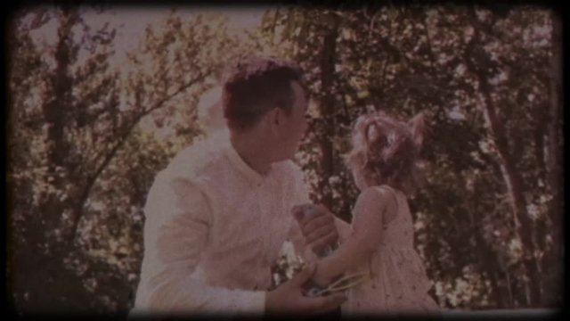 Family video archive. Retro camera 8 mm. Old film. The young father blows soap bubbles with his daughter and son. Family games near the house. Holiday, holidays. Family together