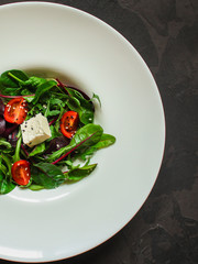 Healthy salad, leaves salad mix in a white plate and cheese (green, juicy snack). food background - Image