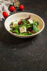Healthy salad, leaves salad mix in a white plate and cheese (green, juicy snack). food background - Image