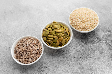 Assortment of nuts in white saucers on a concrete background. Food mix background, top view, copy space, banner