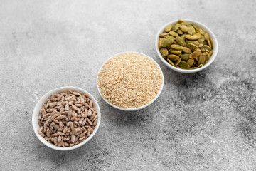 Assortment of nuts in white saucers on a concrete background. Food mix background, top view, copy space, banner