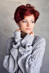 Portrait of a beautiful young red-haired woman with short hair wearing warm woolen sweater