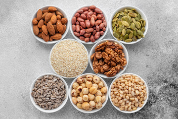 Assortment of nuts in white saucers on a concrete background. Food mix background, top view, copy...