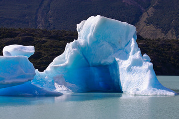 Large blue bright icebergs float on the waters of Lago Argentino lake, El Calafate, Argentina in sunshine day.