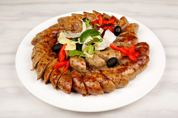 Baked sausage sliced with vegetables on a large platter.