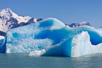 Large blue bright icebergs float on the waters of Lago Argentino lake, El Calafate, Argentina in sunshine day.