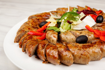 Baked sausage sliced with vegetables on a large platter.
