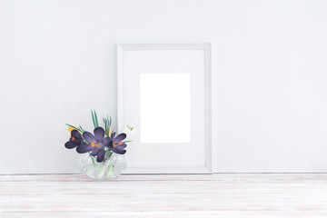 Empty white wooden frame and flowers in vase on white background with copy space. Mockup.