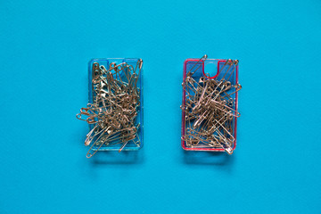 Safety pins  in blue and pink plastic boxes on blue background