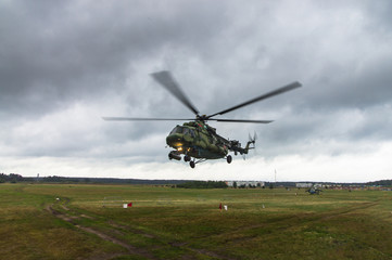 Fototapeta na wymiar Military helicopter takes off from a grass field in the background of the city