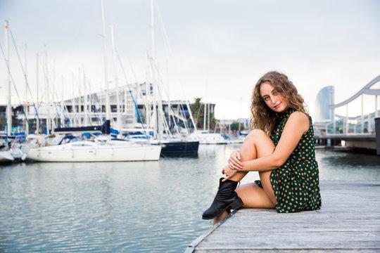 Young attractive woman tourist  sitting at quay  with sailboats on background