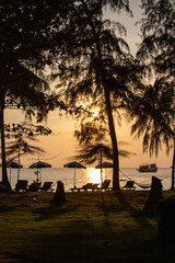 Sonnenuntergang am Strand mit Palmen und Liegen