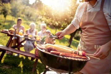 Man preparing food on garden barbecue - obrazy, fototapety, plakaty