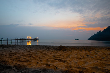 Fototapeta na wymiar Bootssteg, Strand, undFischerboot in der Abenddämmerung