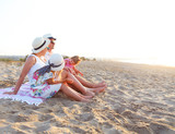 Laughing family with father, mother, daughters having picnic at the beach