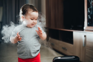 a little girl in red pants looks and touches the humidifier. Moisture in the house concept