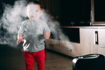 a little girl in red pants looks and touches the humidifier. Moisture in the house concept