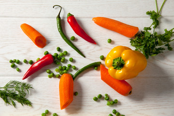 Green pepper, red hot pepper and yellow big pepper. Dill, peas and parsley with wood pattern and over white background