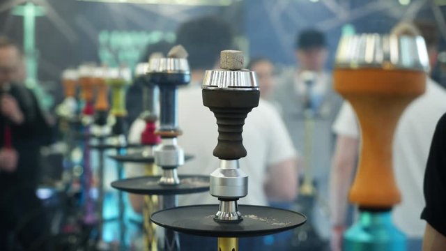 People choosing hookah. Smoking tobacco at exhibition. Shisha bowl at event